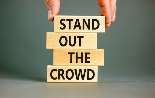Blocks stacked on top of each other with the text, “stand out from the crowd” written on them.