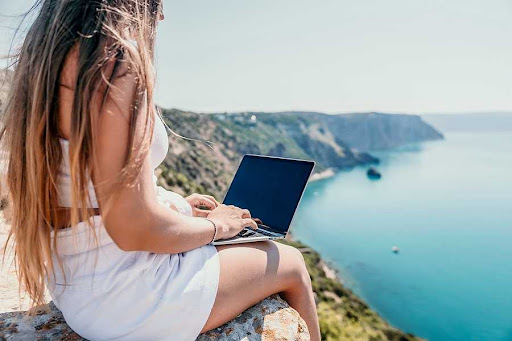 Young investor on her laptop doing virtual real estate wholesaling from exotic location.