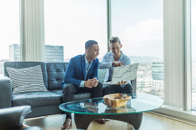 real estate investor showing friend how to find real estate investors on laptop