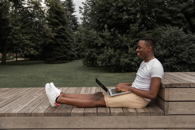 Young investor on laptop in the park video calling connections to find real estate investors