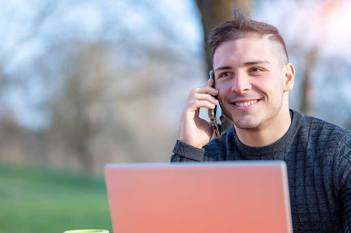 young real estate investor on laptop in the park calling motivated seller he found contact information for through skip tracing