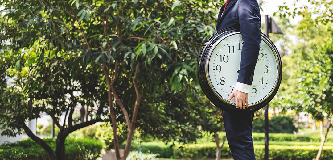 Business man holding clock symbolizing timing your investments