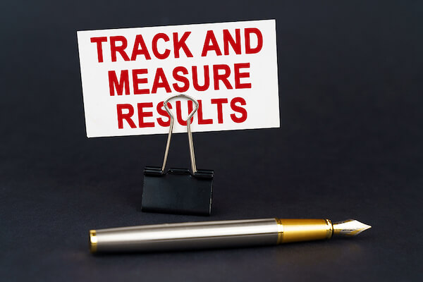 Calligraphy pen on a table with the phrase, "track and measure results"